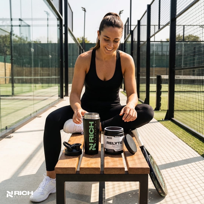 Vrouw op padelbaan met RichNutrition RELYTE Electrolytes en steel shaker